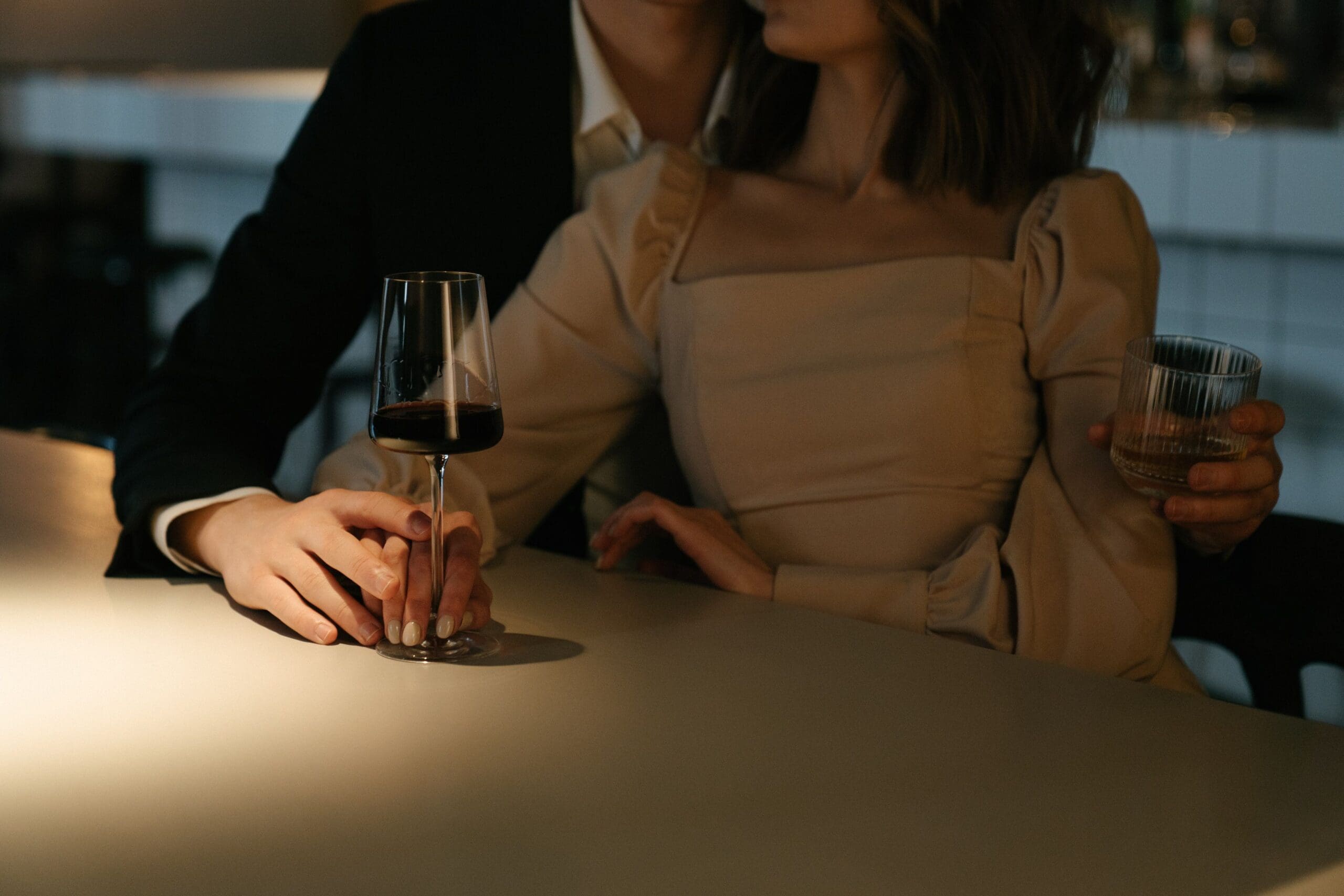 close up of woman in dress with man in black suit holding a wine glass